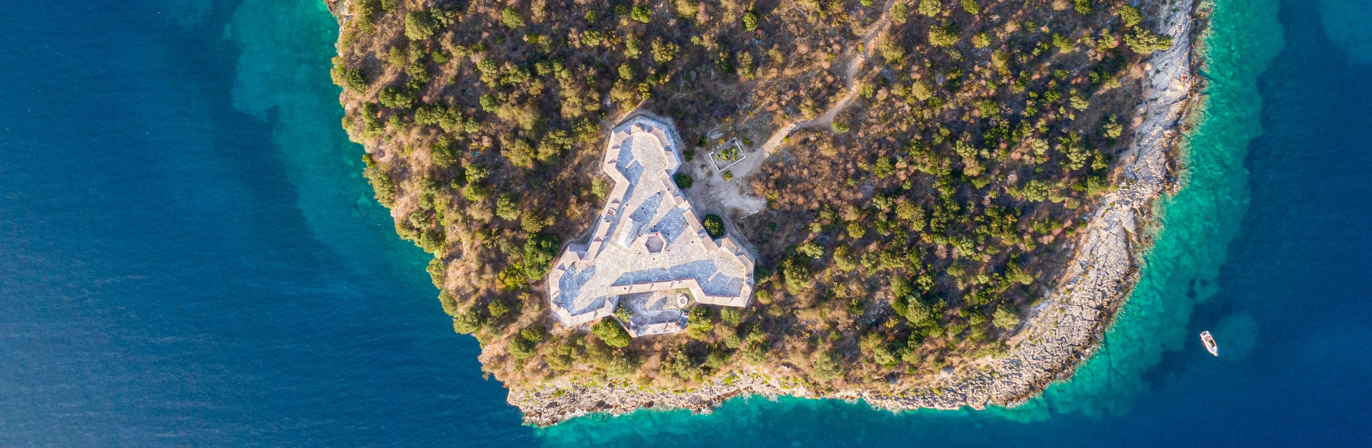 Aerial view of a triangular stone fortress on a rocky peninsula in the Albanian sea