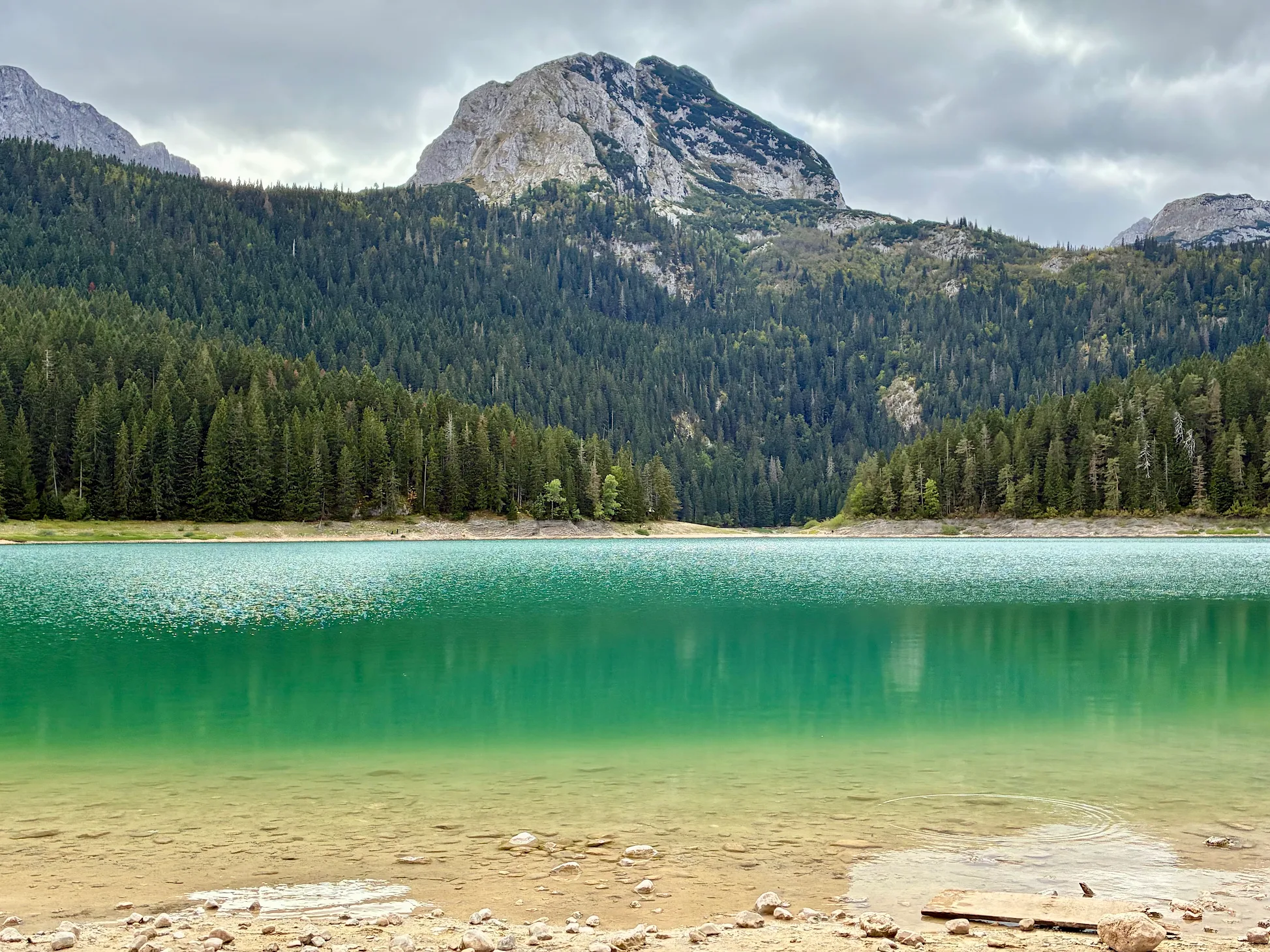 Mountain road beside a turquoise lake in the Albanian mountains